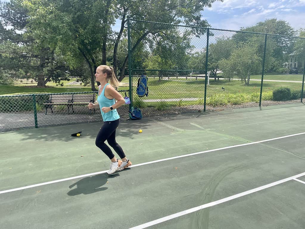 athletic woman jogging to warm up for pickleball